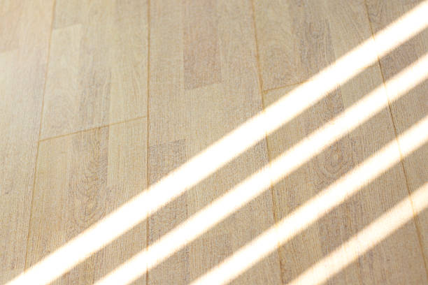 Sunlit wooden floor with diagonal light stripes adds warm, tranquil mood to a home space.