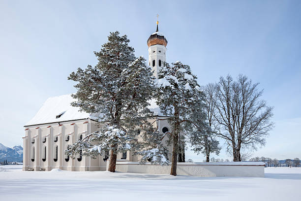 A beautiful old small St. Coloman's church and snow covered trees in a winter scenery under blue sky in Schwangau, Allgau, Bavaria, Germany.