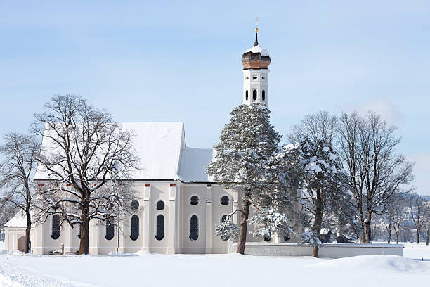 A beautiful old small St. Coloman's church and snow covered trees in a winter scenery under blue sky in Schwangau, Allgau, Bavaria, Germany.