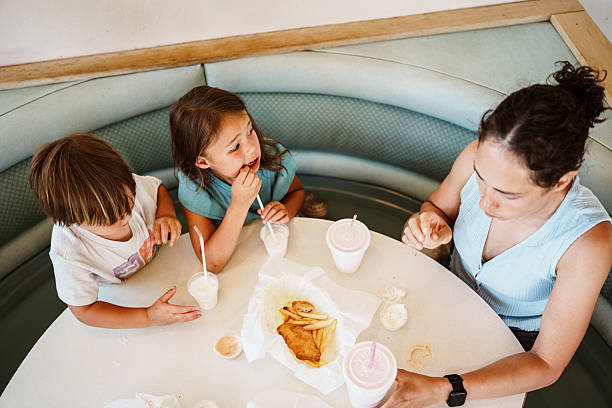 Overhead view of a family with young children sharing a relaxed meal together at a small-town diner.