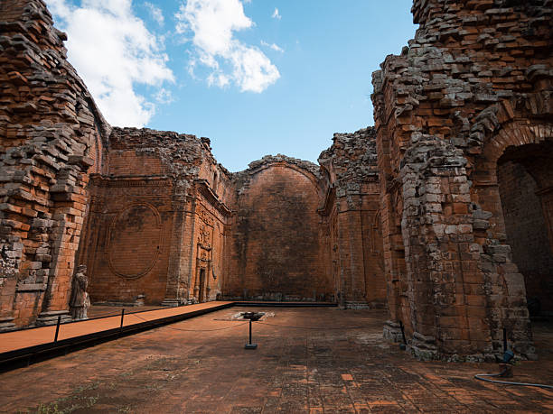Interior scene of a ruined construction with brick walls and arches, illuminated by natural light. Useful for topics of history, architecture, archaeology, heritage, tourism and culture.