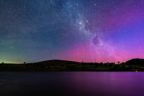 The Southern Lights and the Milky Way spill across the night sky, pink aurora streaks glowing above Carcoar Dam in Central West NSW.