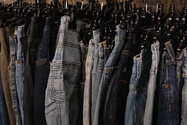 denim pants in different colours hanging on a hangers on  a clothing rack