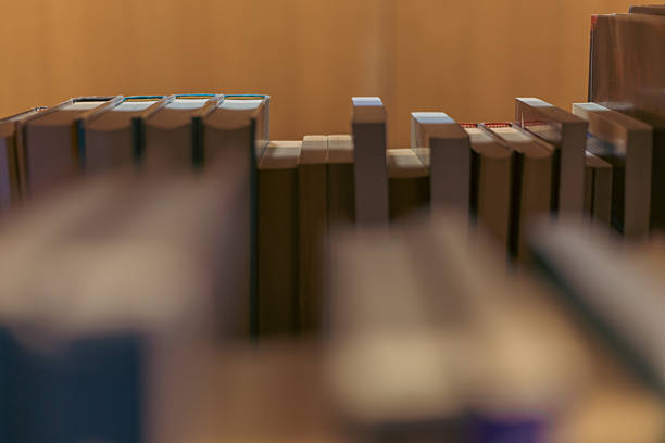Rows of bookshelves filled with numerous books line a library aisle, creating a warm and inviting atmosphere. The background is softly blurred, showcasing th...