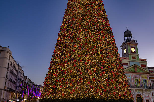 Madrid. Spain. Giant decorated christmas tree standing at puerta del sol square in madrid, illuminating the city with warm holiday lights during twilight, reflecting the festive season atmosphere