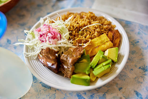 Close-up of rice, chicken, plantain, avocado, and cabbage salad.