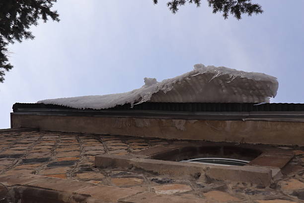 A wooden house covered with a large layer of ice and icicles. Mountainous terrain.