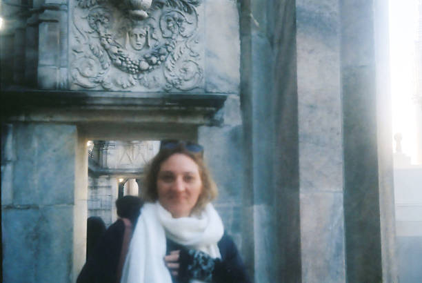 Smiling woman on the rooftop of Duomo Cathedral in Milan, Italy. Analog film portrait with natural light, historic Gothic architecture, and panoramic city views. Concept of travel, tourism, European culture, lifestyle, and timeless vintage photography.