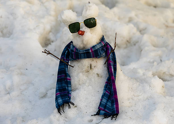 cute handmade snowman with sunglasses standing in fresh snow