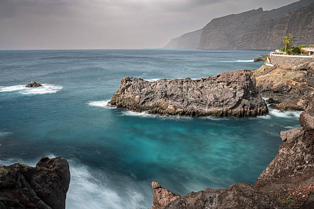 The rugged coast of Los Gigantes, Tenerife, Canary Islands, features its famous dramatic cliffs and turquoise waters, captured with a captivating slow exposure.