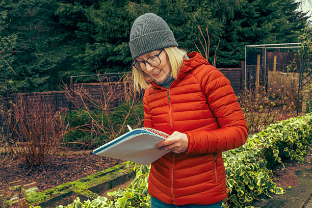 Woman in her greenhouse noting down jobs to be done and things to buy during winter.