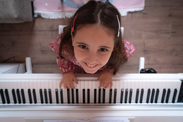 Little happy girl playing piano. Cute child having fun with learning to play music instrument.