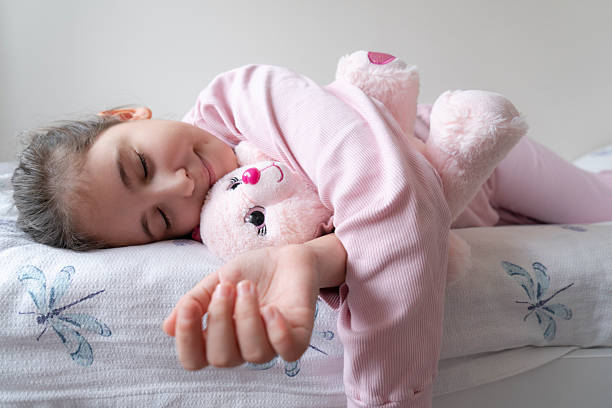 little girl in bed sleeping with her teddy bear
