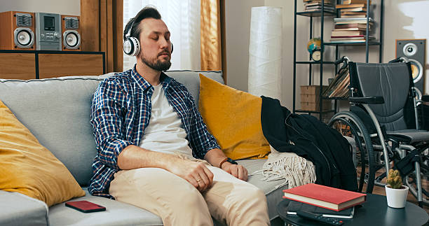 A man with dark hair scrolls through social media, thinking about what to post. With his wheelchair in the background, he searches his photo gallery for highlights from the past week.