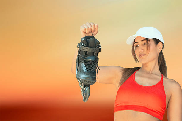 Young adult woman holding a rollerblade feeling empowered against a warm background