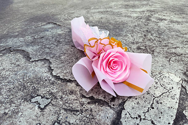 pink handmade satin ribbon rose bouquet on grey concrete background.