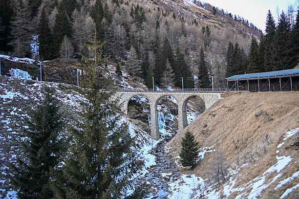 Historic stone viaduct carrying railway tracks through snowy winter mountains