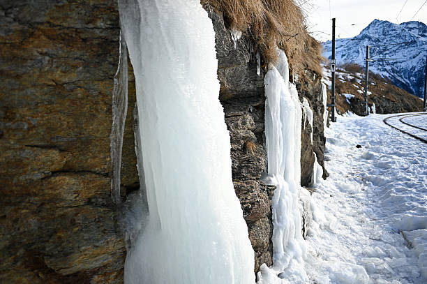 Winter scene showing ice formation cascading down a brick building's facade, creating a striking visual effect in the cold weather.