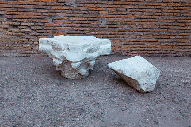 Rome Italy October 3 2025 Ancient stone ruins and broken marble architectural elements placed near a brick wall at an archaeological site in Rome The remains illustrate classical Roman architecture history and cultural heritage preserved in open air museum conditions
