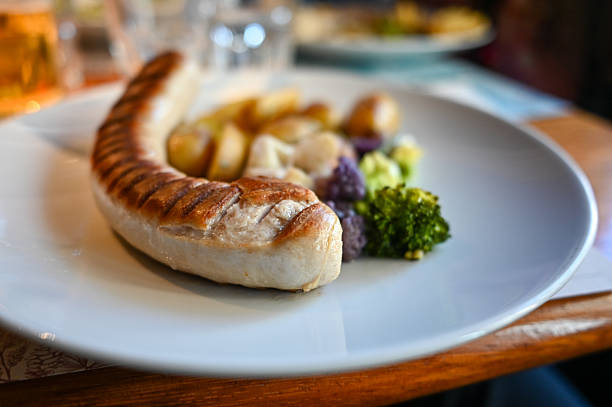 Grilled bratwurst sausage served with roasted potatoes, broccoli, and purple cauliflower on a white plate