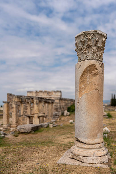 Stone ruins display remains of ancient public latrine with partial walls and seating structures visible at Hierapolis, Turkey. The fragmentary building shows characteristic Roman sanitation facility architecture with substantial stone construction. The ruined latrine represents the public amenities essential to Hierapolis's function as spa city, where large numbers of visitors required extensive public facilities, with the latrines serving important role in Roman urban infrastructure providing hygienic waste disposal for the thousands who congregated at this famous therapeutic destination.