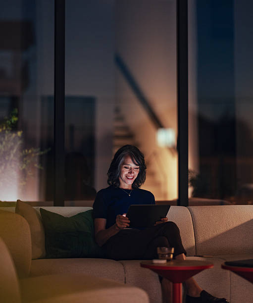 Relaxed Senior Woman Using Tablet On Couch At Night In Cozy Home Setting