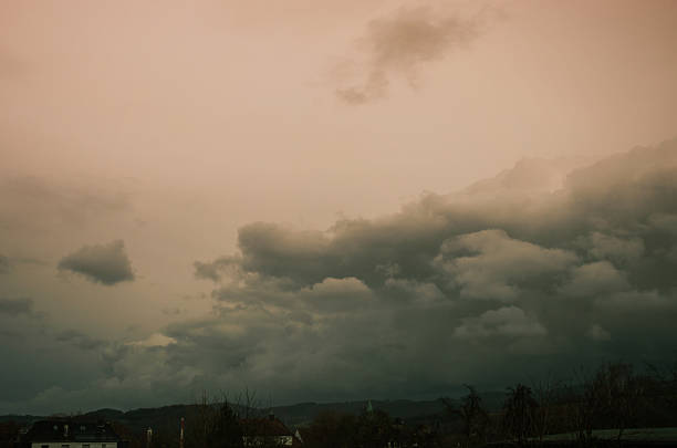 Dramatic storm clouds gather over a quiet European village at dusk