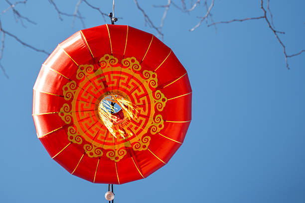 Decorative red Chinese lantern hanging outdoors against a clear blue sky, symbolizing celebration and cultural traditions during the Chinese New Year festival.