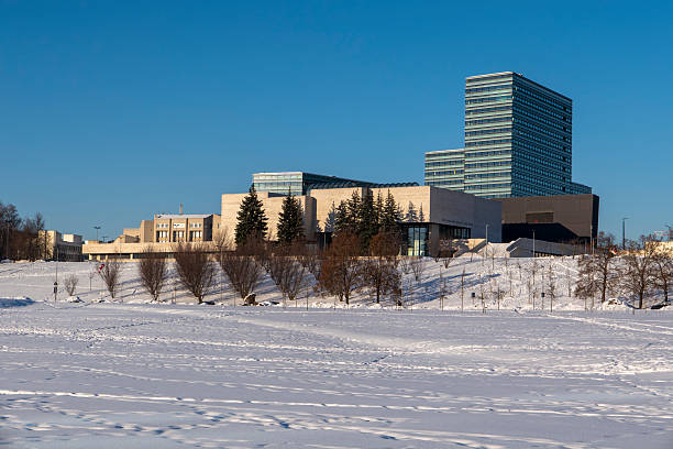Winter cityscape of Vilnius, Lithuania, featuring the frozen Neris River and a modern urban skyline under clear blue sky. Snow-covered ice formations and contemporary architecture create a strong visual contrast, ideal for climate, winter weather, urban lifestyle, and European city concepts.