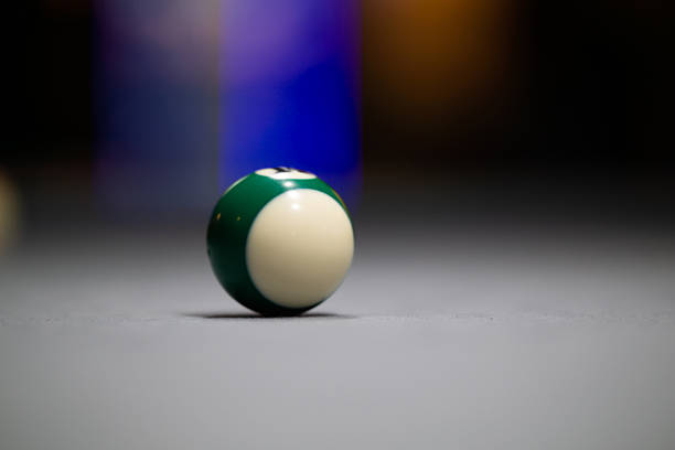 Close-up of a bright yellow billiard ball resting on a green table, captured with shallow depth of field. The glossy surface, soft reflections, and blurred background sporting atmosphere.