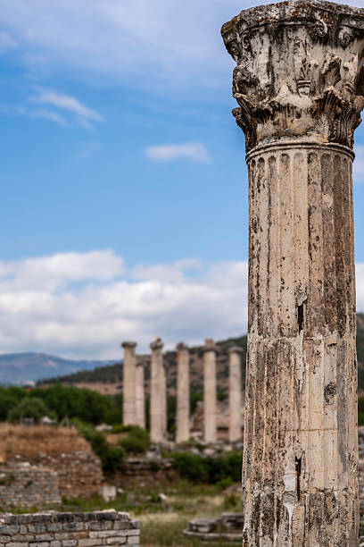 Ornate Corinthian capital displays elaborate acanthus leaf carving with distinctive volutes at Aphrodisias bishop's palace, Turkey. The detailed marble capital shows characteristic late antique architectural decoration with sophisticated sculptural ornament. The elaborate column capital represents the architectural refinement of the bishop's palace built during Aphrodisias's Christian period, demonstrating how the city's famous sculptural workshops continued producing beautiful carved architectural elements even as Aphrodisias transformed from pagan center dedicated to Aphrodite into Christian episcopal seat, adapting their skills to new religious architecture.
