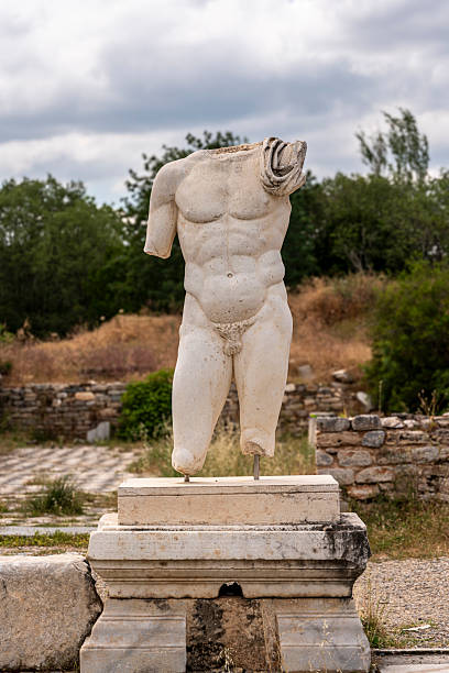 An exquisite statue presenting three women in close embrace, symbolizing unity and grace. The artwork, steeped in classical influence, captures timeless beauty and intricate artistry in monochrome, standing serenely amidst tranquil surroundings.