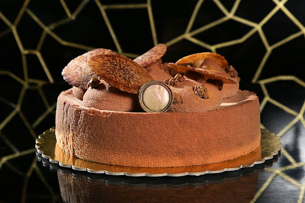 Chocolate mousse cake with decorative chocolate discs and biscuit toppings on dark background