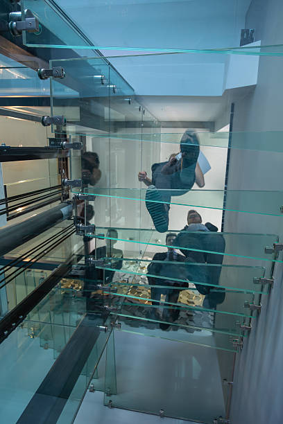 A top-down view of a modern spiral staircase with curved marble steps and glass railings.