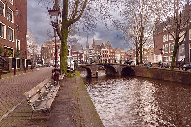 Historic canal bridge with traditional houses and church in Amsterdam, Netherlands