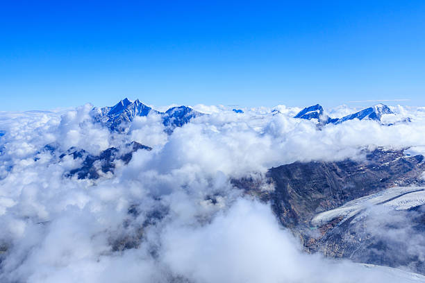 Panorama with mountain summits Dom, Alphubel, Rimpfischhorn and Strahlhorn (left to right) over cloudscape in summer in Swiss Alps, canton of Valais, Switzerland