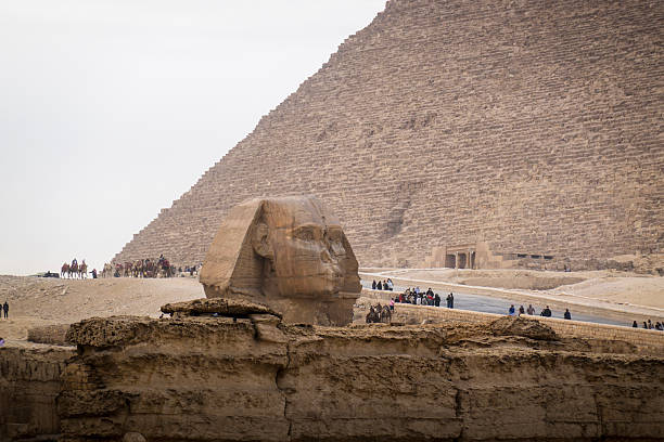 Cairo, Egypt- February 01, 2026: Majestic Great Pyramids and Camel Riders Under a Hazy Sky