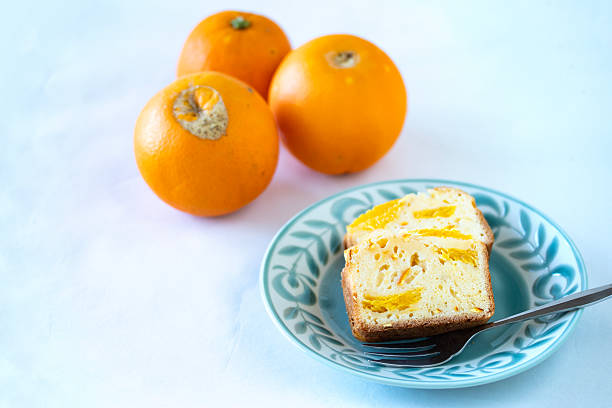 Fresh navel oranges and orange pound cake on a plate.
