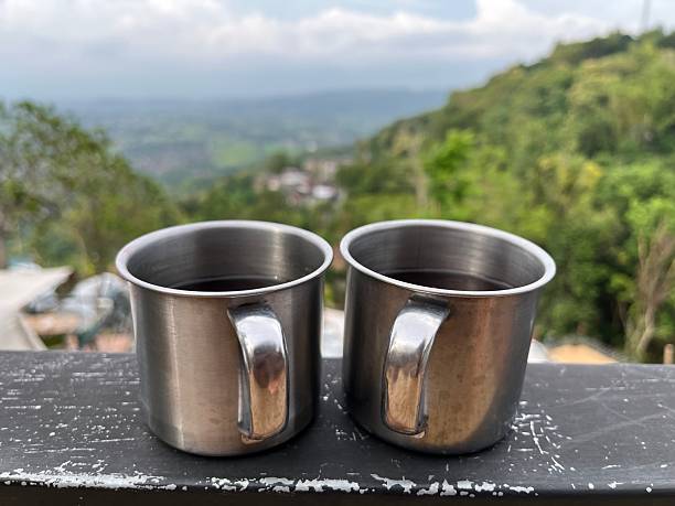 Two stainless steel mugs of hot coffee on a balcony