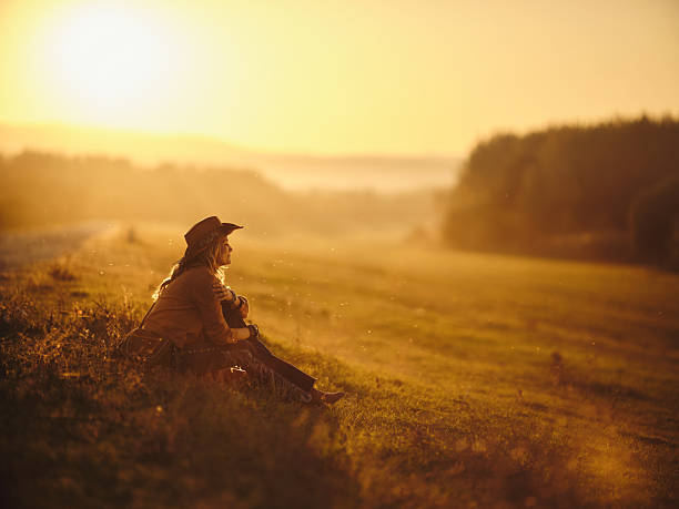Smiling female rancher day dreaming while relaxing in grass at sunset. Copy space. Photographed in medium format.