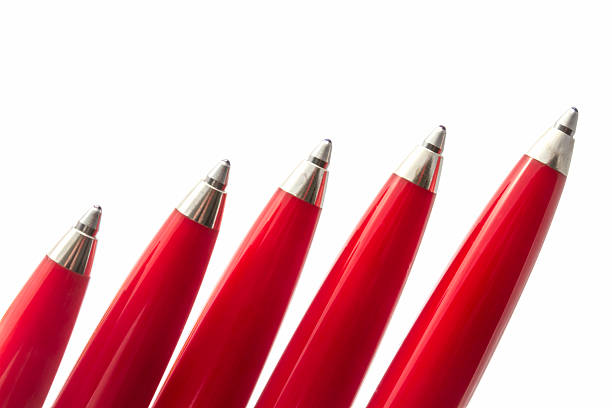Group of five shiny red ballpoint pens with silver tips are positioned in a diagonal line against a clean white backdrop