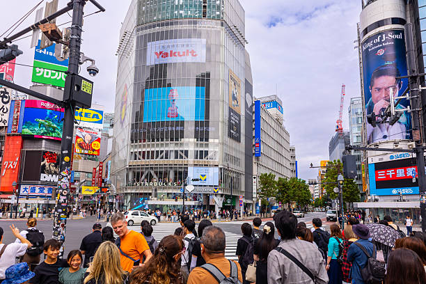 Tokyo, Japan - October 7, 2025: Metropolitan movement framing. Famous Shibuya intersection surrounded by advertising screens traffic and pedestrians Japan travel destination.