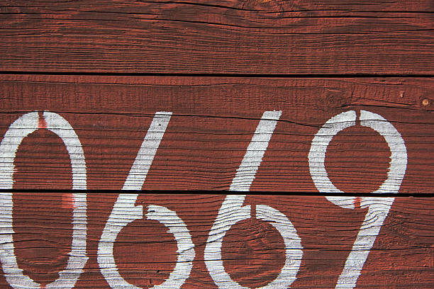 Stenciled White Numbers on Weathered Red Wooden Surface