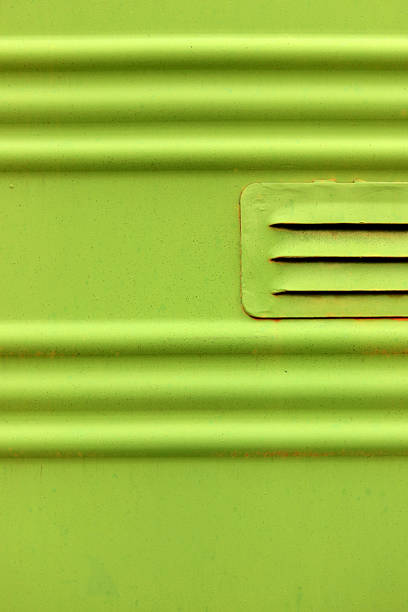 Closeup of an old green wooden front door, with brass mail slot.