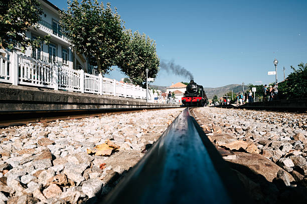 Douro valey, portugal; july 27, 2024: steam locomotive traveling on railway track with passengers waiting on platform