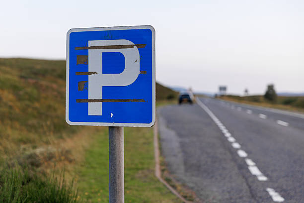 Blue parking sign on a rural roadside with an empty highway stretching into the distance.