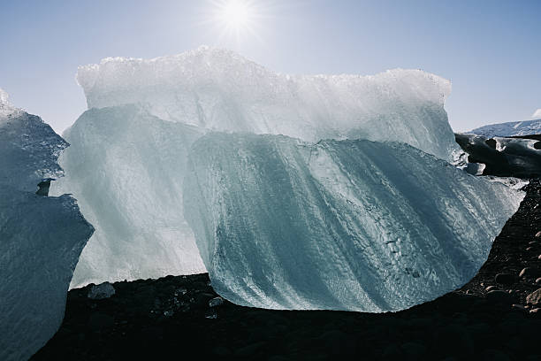 Iceberg chunks washed ashore on the famous black sand shore of Diamond Beach, part of the Jökulsárlón glacier lagoon outflow, reflecting the bright sun and cold arctic winter light