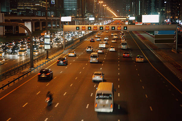 High-angle view of cars and trucks traveling along an elevated highway illuminated by streetlights and signage. The scene reflects urban transportation networks, logistics, and the constant movement that defines large metropolitan areas.