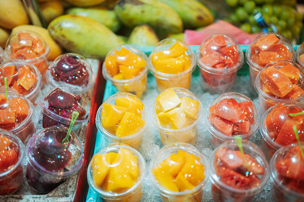 assorted asian fruit cups prepared for takeaway including mango watermelon and tropical selections highlighting healthy snack culture in busy night market environment