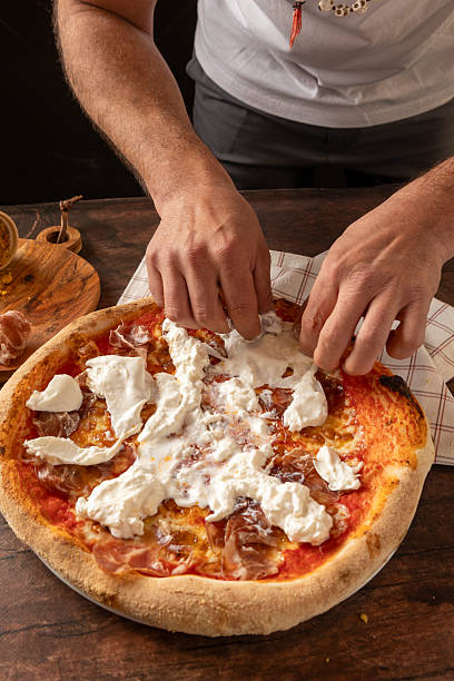 Chef hands topping pepperoni pizza with burrata cheese